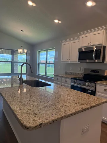 a kitchen with stainless steel appliances granite countertop a sink a stove and a microwave