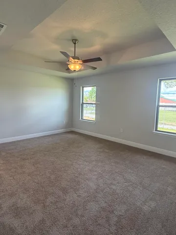 en empty room with windows and ceiling fan