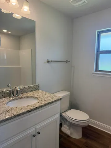 a bathroom with a granite countertop toilet a sink and mirror
