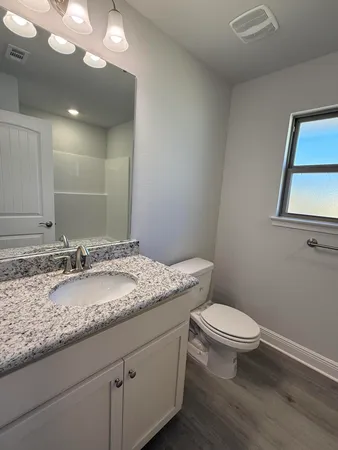 a bathroom with a granite countertop sink mirror and toilet