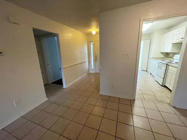 a view of a refrigerator in kitchen and an empty room