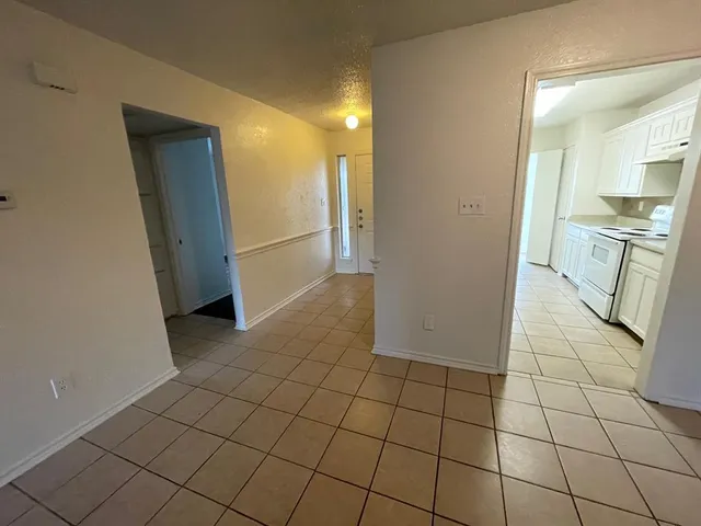 a view of a refrigerator in kitchen and an empty room
