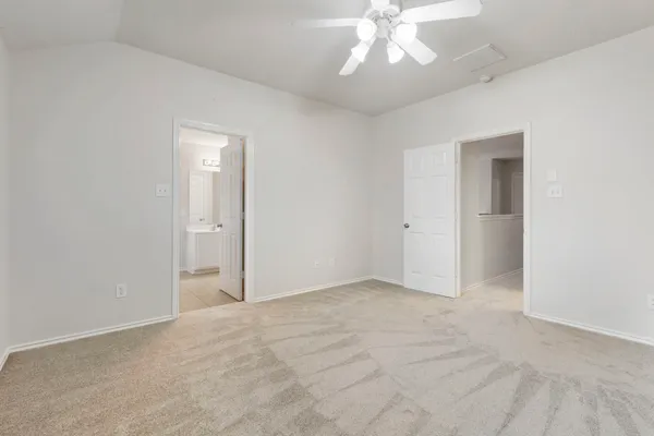 an empty room with a chandelier fan and windows
