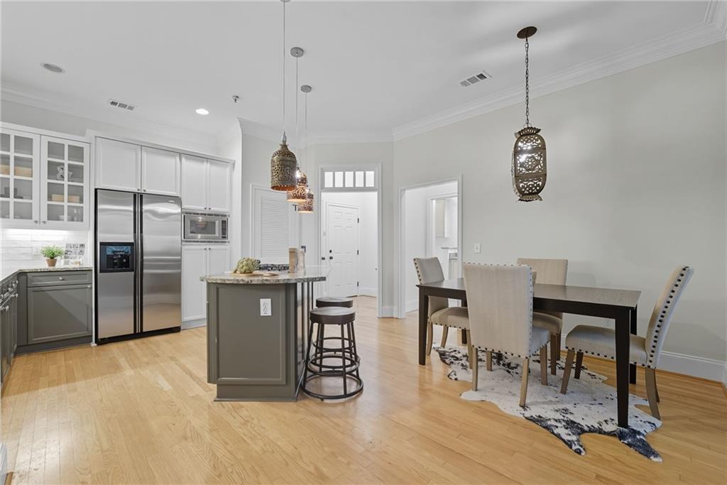 825 Highland Lane Northeast, Unit 1312 Atlanta, GA 30306 - Photo 18 of 46 a kitchen with stainless steel appliances kitchen island granite countertop a refrigerator a stove a dining table and chairs with wooden floor