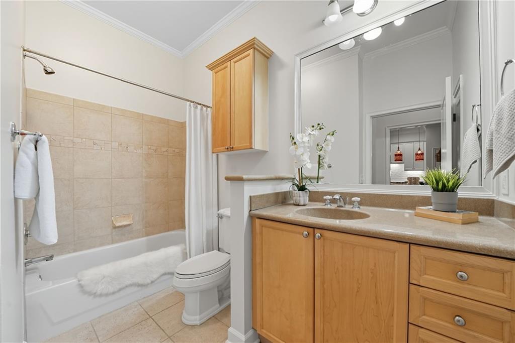 825 Highland Lane Northeast, Unit 1312 Atlanta, GA 30306 - Photo 34 of 46 a bathroom with a granite countertop sink toilet a large mirror a shower and a bathtub