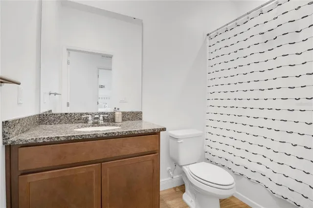 a bathroom with a granite countertop toilet a sink and a mirror