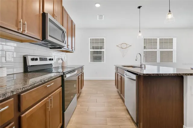 a kitchen with stainless steel appliances granite countertop a sink and dishwasher a stove top oven with wooden floor