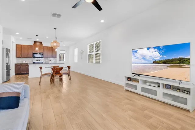 a living room with stainless steel appliances furniture a rug and a view of kitchen