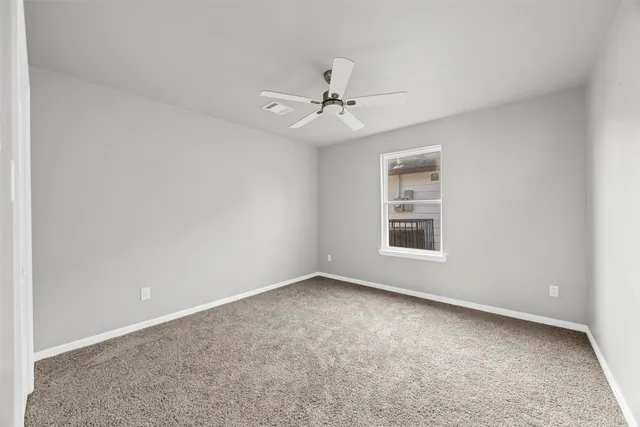 an empty room with a window and ceiling fan