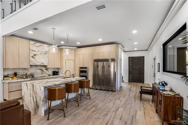 a kitchen with stainless steel appliances a dining table chairs refrigerator and sink