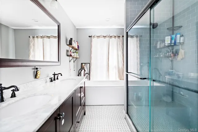 a bathroom with a tub sink vanity granite and a shower