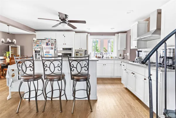 a kitchen with stainless steel appliances kitchen island granite countertop a dining table chairs and white cabinets