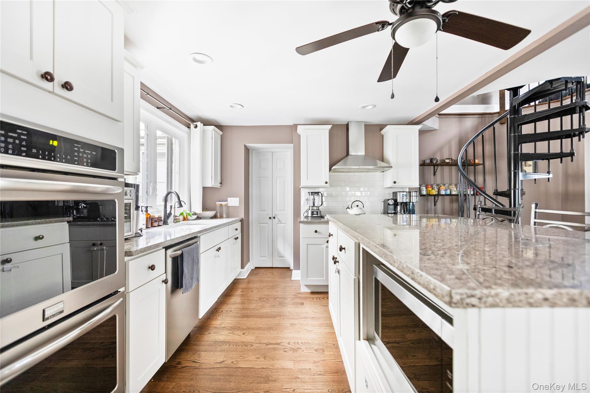 10 Maple Avenue Patchogue, NY 11772 - Photo 9 of 28 Kitchen with stainless steel appliances, white cabinets, light wood-style floors, light stone countertops, and decorative backsplash