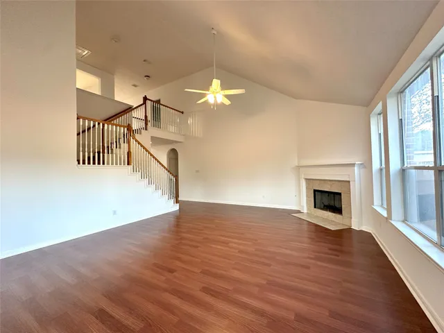 an empty room with wooden floor chandelier fan and windows