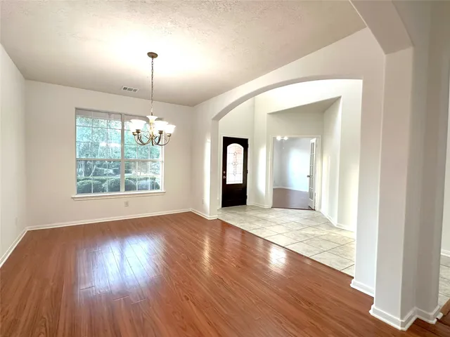 a view of an empty room with wooden floor fireplace and a window
