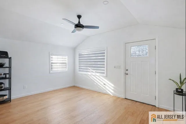 a view of an empty room with a window and wooden floor