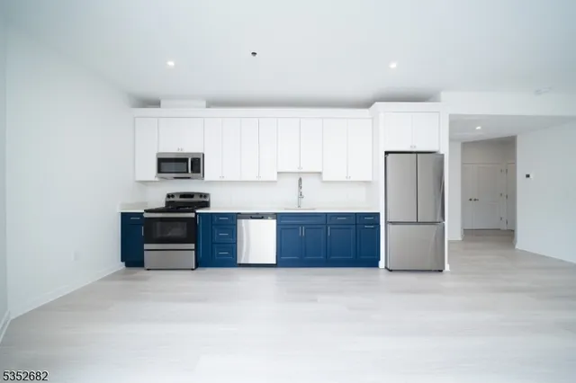 a kitchen with stainless steel appliances a refrigerator a stove a sink a window and white cabinets