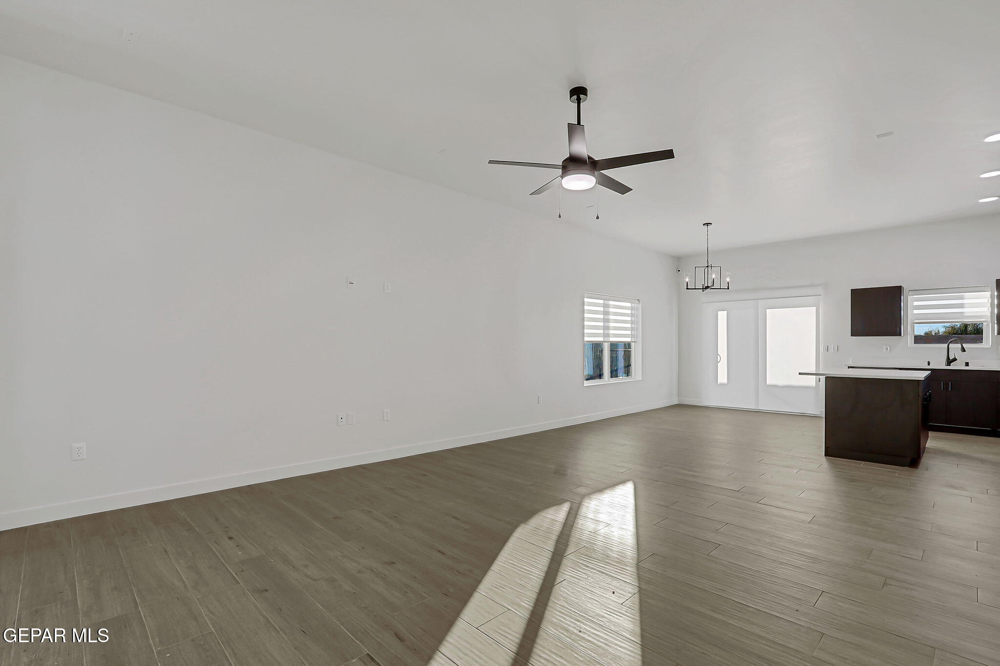 5981 Ruidoso Downs Street El Paso, TX 79932 - Photo 7 of 35 an empty room with wooden floor chandelier fan and windows