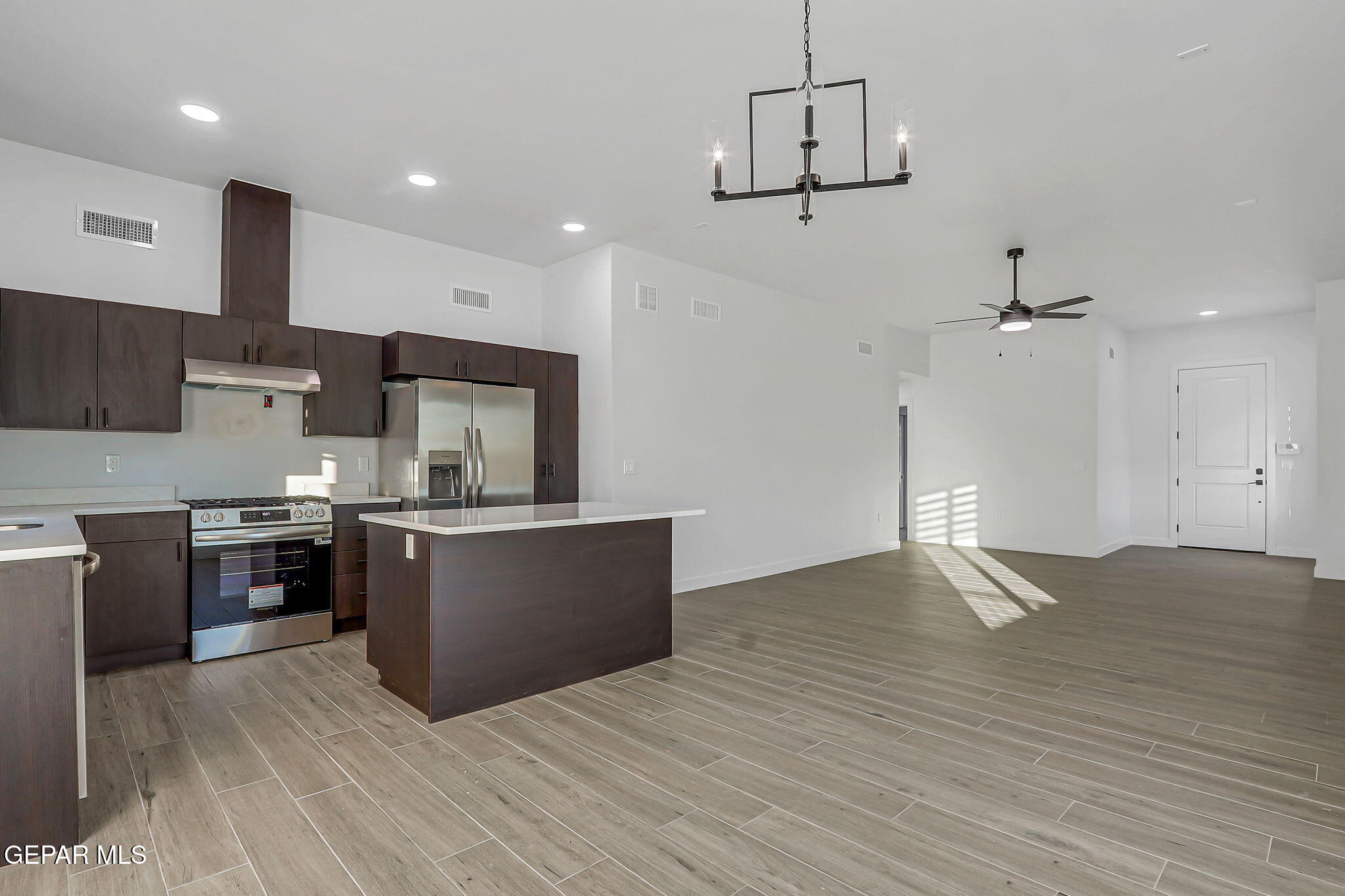 5981 Ruidoso Downs Street El Paso, TX 79932 - Photo 8 of 35 a kitchen with kitchen island stainless steel appliances a stove refrigerator and microwave