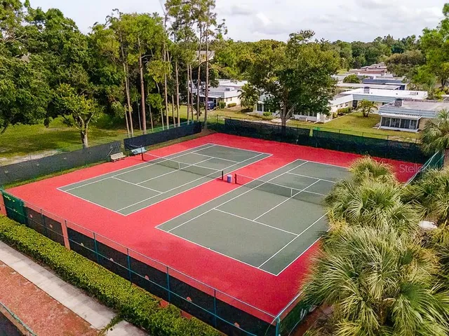 a view of a tennis ground with large trees