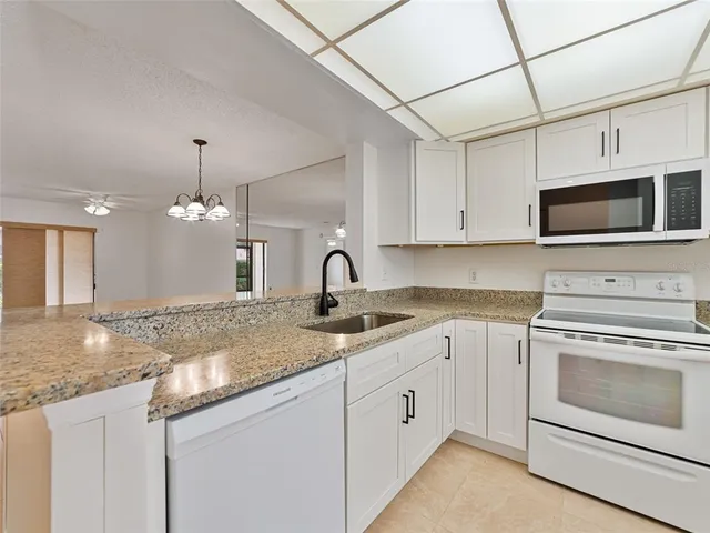 a kitchen with granite countertop a sink stainless steel appliances and white cabinets