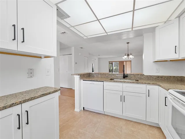 a kitchen with granite countertop white cabinets and a sink