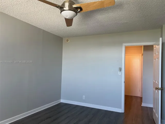 an empty room with wooden floor cabinet and ceiling fan