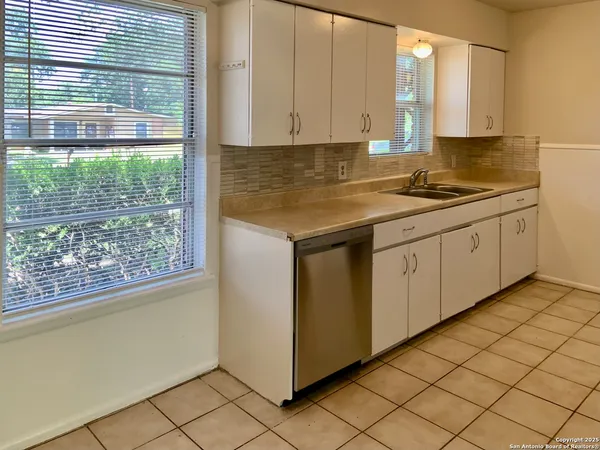 a kitchen with granite countertop white cabinets and a window