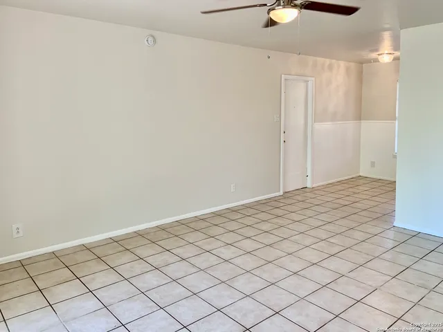 a view of an empty room and chandelier fan