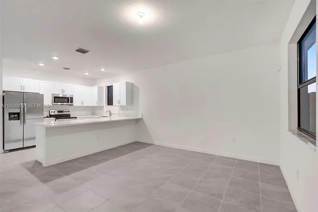 a large white kitchen with white cabinets and a refrigerator
