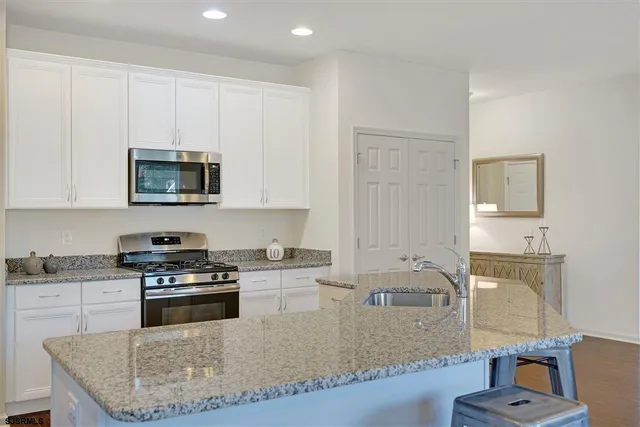 a kitchen with stainless steel appliances granite countertop a stove a sink and a microwave