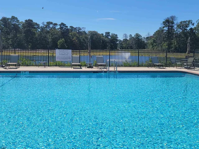 a view of a swimming pool with a bench and trees in the background
