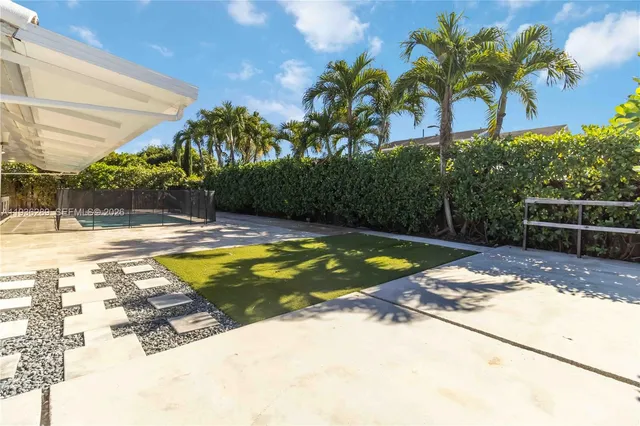 a view of swimming pool with a yard and palm trees