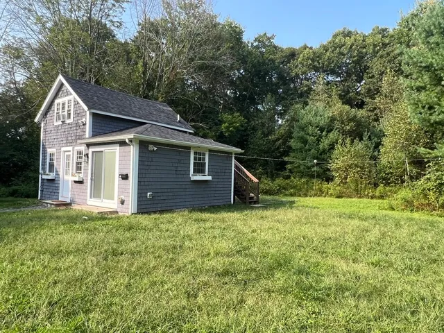 a backyard of a house with plants and large tree