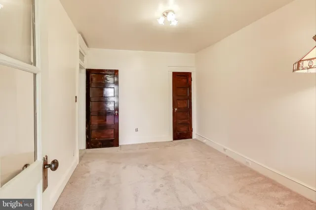 an empty room with chandelier fan and closet area