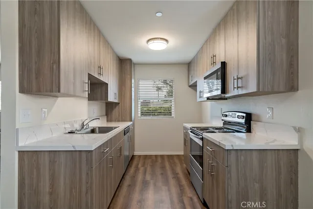 a kitchen with stainless steel appliances granite countertop a stove a sink dishwasher and a microwave oven with wooden cabinets