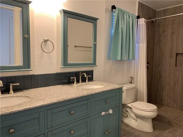 a bathroom with a granite countertop toilet sink and mirror