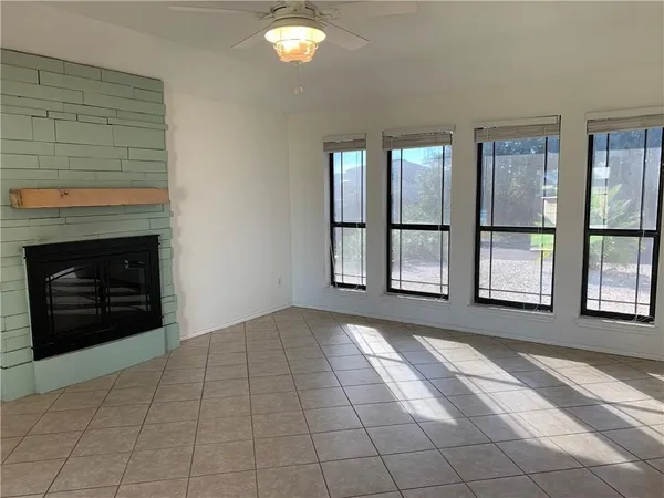 a view of an empty room with windows and fireplace