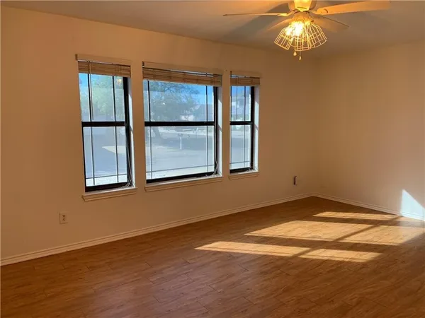 an empty room with wooden floor and windows