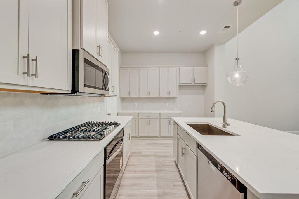 8159 Challenger Lane Frisco, TX 75034 - Photo 4 of 36 a kitchen with stainless steel appliances granite countertop a sink stove and cabinets