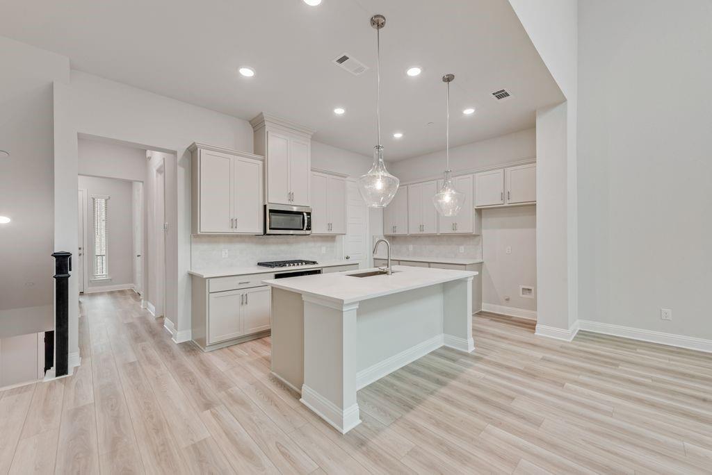 8159 Challenger Lane Frisco, TX 75034 - Photo 5 of 36 a kitchen with stainless steel appliances white cabinets a sink dishwasher a stove and a refrigerator with wooden floor