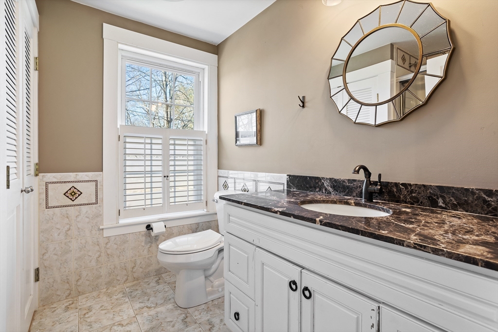 16 Main Street, Unit 3 Pepperell, MA 01463 - Photo 20 of 30 a bathroom with a granite countertop toilet a sink and a mirror