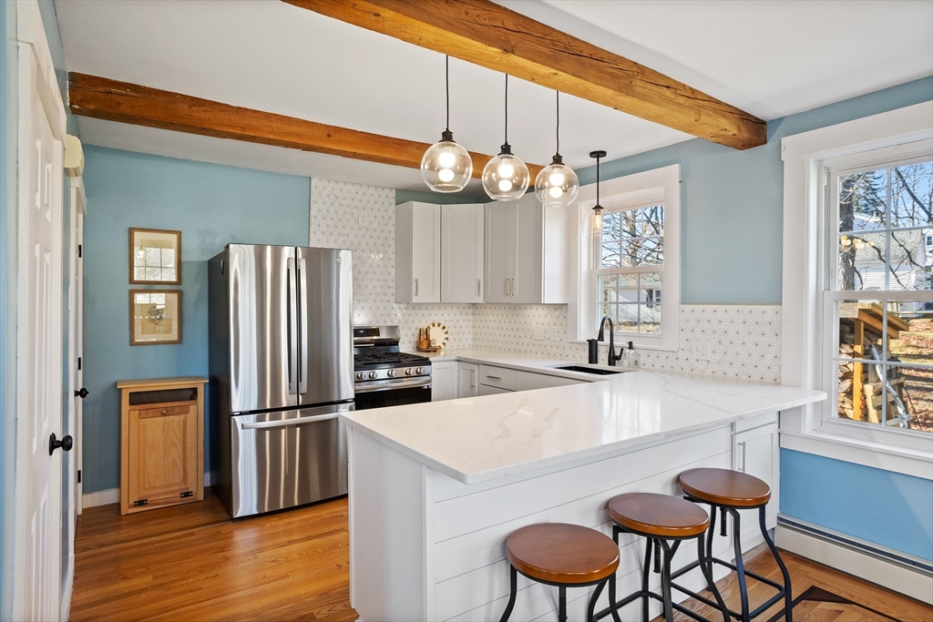 16 Main Street, Unit 3 Pepperell, MA 01463 - Photo 5 of 30 a kitchen with granite countertop a table chairs stove and refrigerator