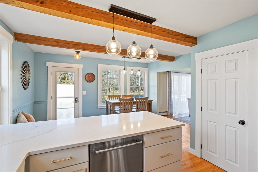 16 Main Street, Unit 3 Pepperell, MA 01463 - Photo 8 of 30 a kitchen with a stove a sink dishwasher and a dining table with wooden floor