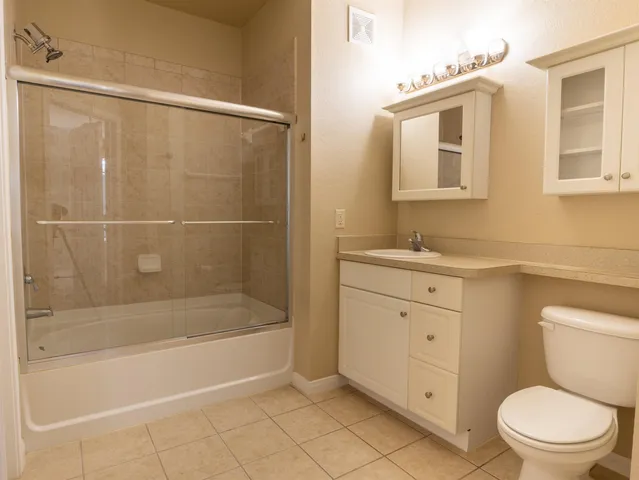 a bathroom with a granite countertop sink a toilet and shower
