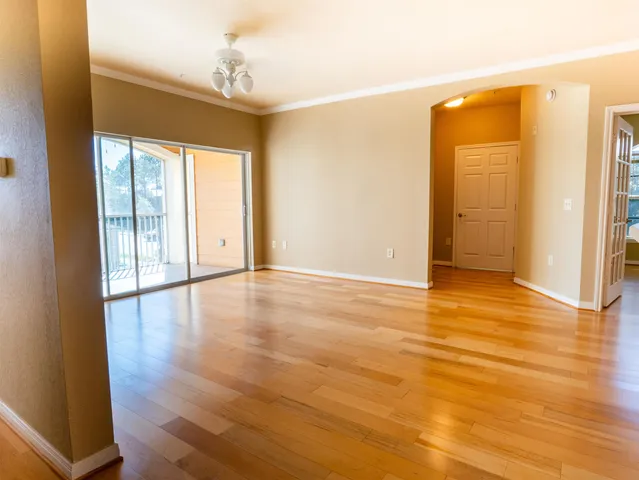 a view of an empty room with wooden floor and a window