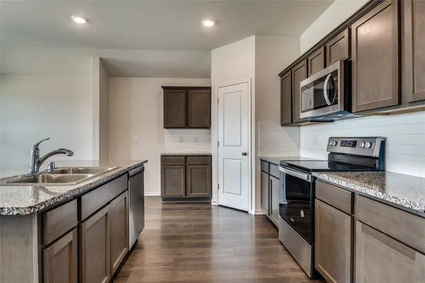 a kitchen with stainless steel appliances granite countertop a sink stove and microwave
