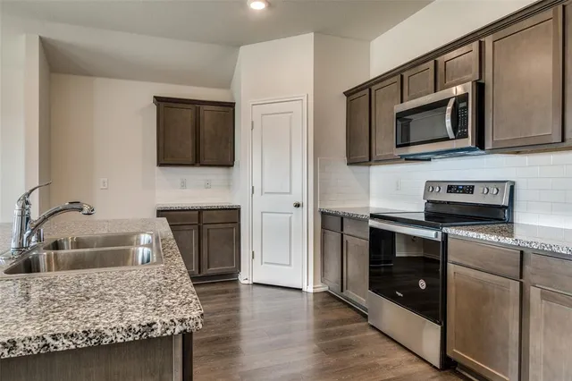 a kitchen with stainless steel appliances granite countertop a stove microwave and sink