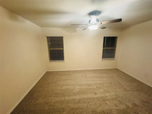 a view of an empty room with chandelier fan and a window