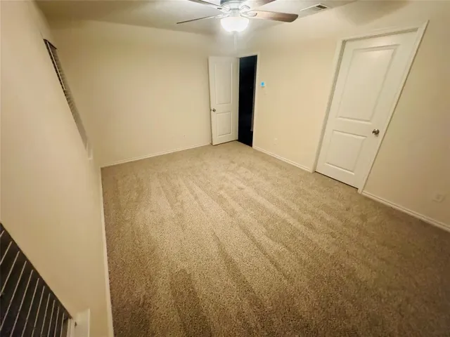 an empty room with a ceiling fan and a window